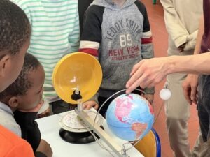 Enfants réunis autour d'une maquette expliquant les phases de la Lune.
