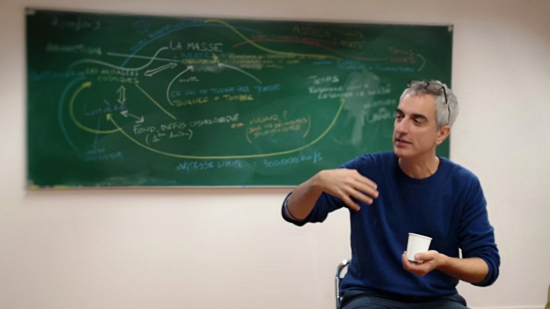 Matteo assis dos à un tableau où il a expliqué les grandes composantes de l'Univers.