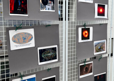 Exposition photographique sur grille métallique lors de la Journée Science : images de télescopes, du fonds diffus cosmologique de la mission Planck, du détecteur ATLAS au CERN, du trou noir Sagittarius A* par Event Horizon Telescope, et du détecteur Virgo en Italie.