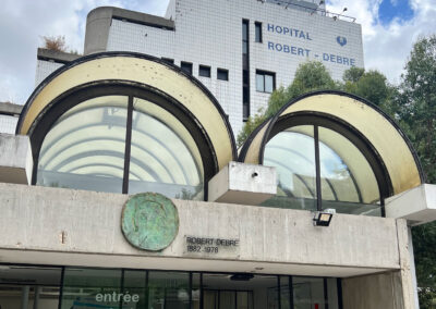 Façade principale de l'hôpital Robert-Debré (Paris) avec ses arches vitrées caractéristiques et la médaille commémorative en bronze de Robert Debré (1882-1978). Entrée principale au 48 boulevard Sérurier.